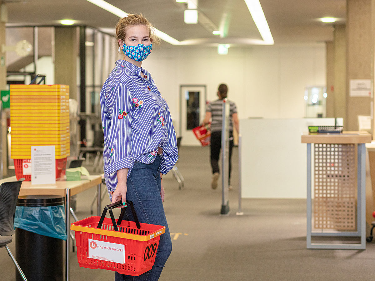 A student wearing a face mask in the library's entrance hall.