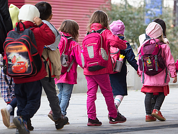 Eine Gruppe von Kleinkindern mit bunten Jacken und Rucksäcken.