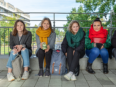 Vier Studentinnen sitzen am Geländer vom Boulevard.