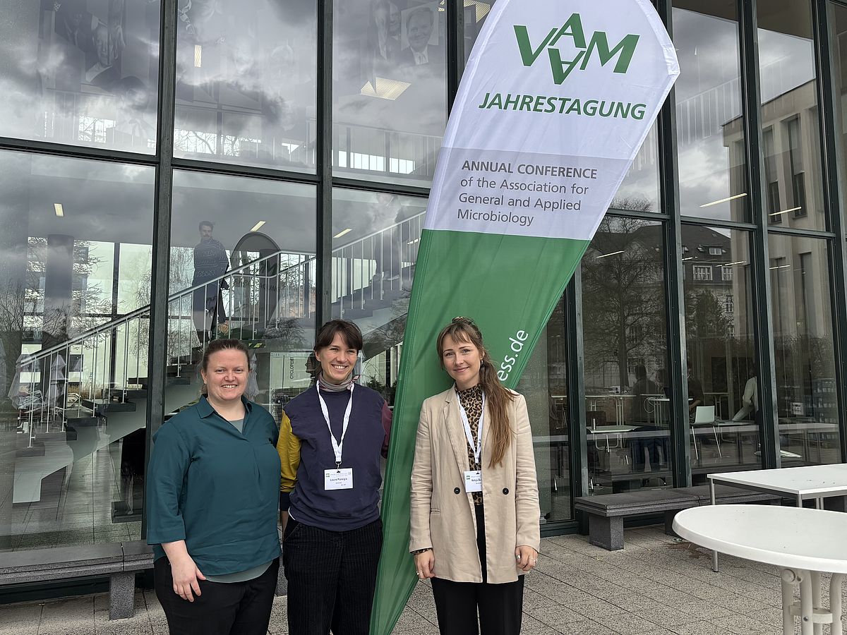 Drei Frauen stehen vor dem Banner der VAAM 2026 in Berlin