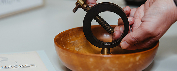 A bowl with a device for cracking nuts, standing on a paper flyer.