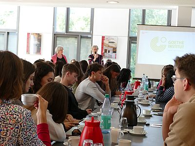 Zwei Frauen sprechen über Kurse des Goethe-Instituts, Studierende im Vordergrung
