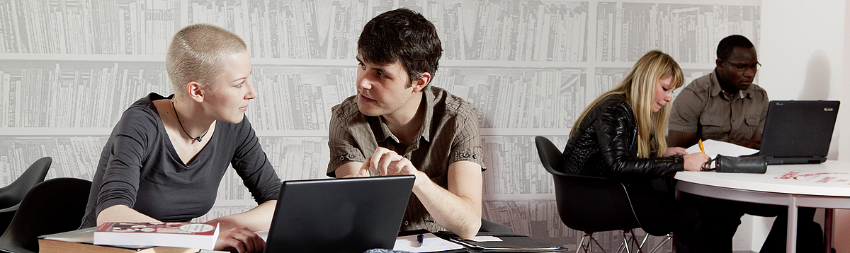Two students working together on a laptop.