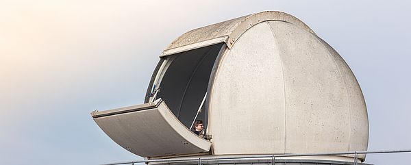 A white dome with an open flap on the roof of a building