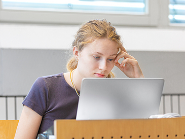 Eine Studentin schaut während einer Vorlesung auf ihren Laptop