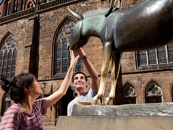 Two people look at the monument to the Bremen Town Musicians.