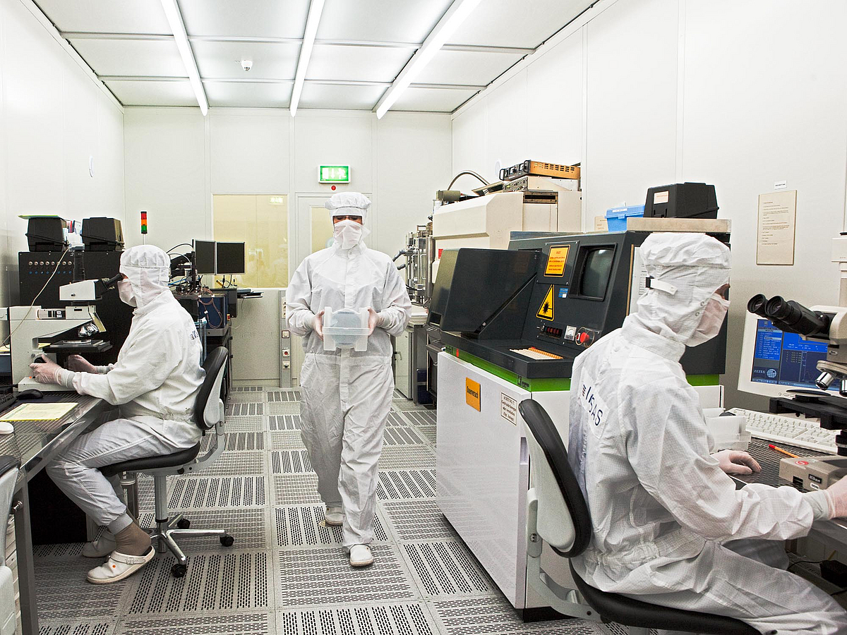 Drei Personen in Schutzkleidung bei der Arbeit im Labor.
