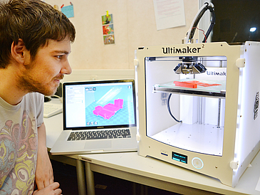 Young man with computer and 3D printer