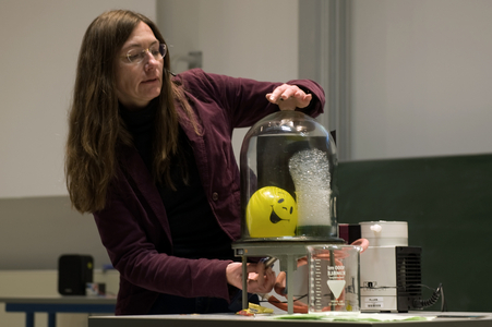 Frau Seebald präsentiert einen Versuch, wie sich ein Luftballon und Seifenlauge im Vakuum n einer Glasglocke verhalten.