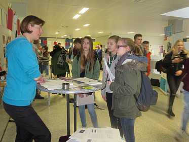 Drei Schülerinnen im Gespräch mit einer Erwachsenen.
