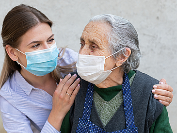 Pflegerin und Bewohnerin eines Pflegeheimes mit Masken