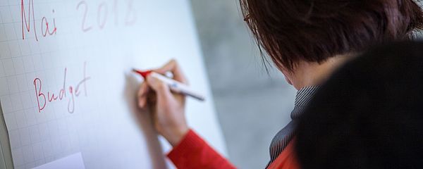 Eine Lehrende schreibt auf ein Flipchart.