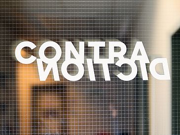 Schriftzug "Contradiction" an einer Glastür
