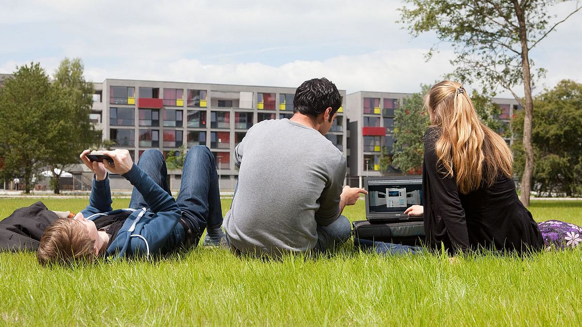 Studierende auf einer Wiese im Campuspark.