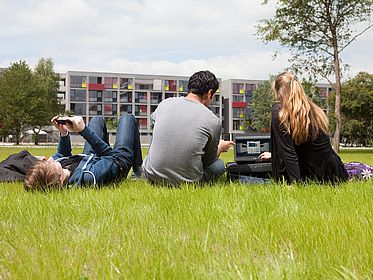 Studierende auf einer Wiese im Campuspark.