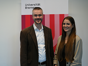 EARIE 2025 Johannes Paha Professor Doktor Johannes Paha neben Wiebke Siebert vor einem Rollup der Universität Bremen