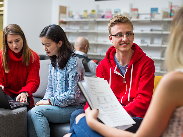 Studierende arbeiten mit einem Laptop und Unterlagen.