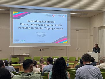 Sara Doolittle Llanos steht im Vorlesungssaal am Rednerpult und spricht zum Publikum