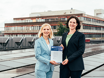 Professor Jutta Günther, President of the University of Bremen, and Senator for the Environment, Climate, and Science Kathrin Moosdorf between the solar panels on the roof of the campus Mensa cafeteria.