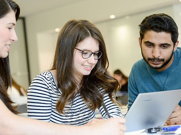 Young people work at a laptop.
