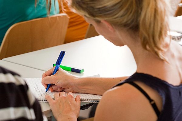 A student takes notes in a seminar room.