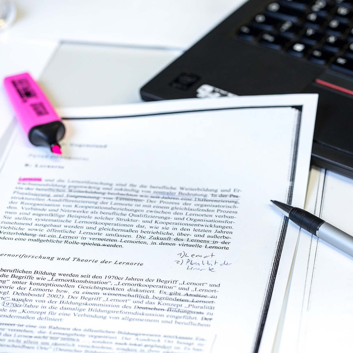 Arbeitsplatz mit Laptop, Zettel und Stift.