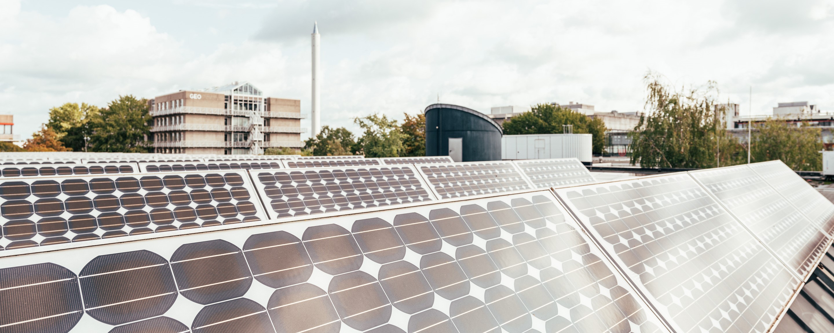 Mehrere Photovoltaikanlagen auf dem Dach der Mensa der Universität Bremen. Im Hintergrund sind Teile das Campus zu sehen