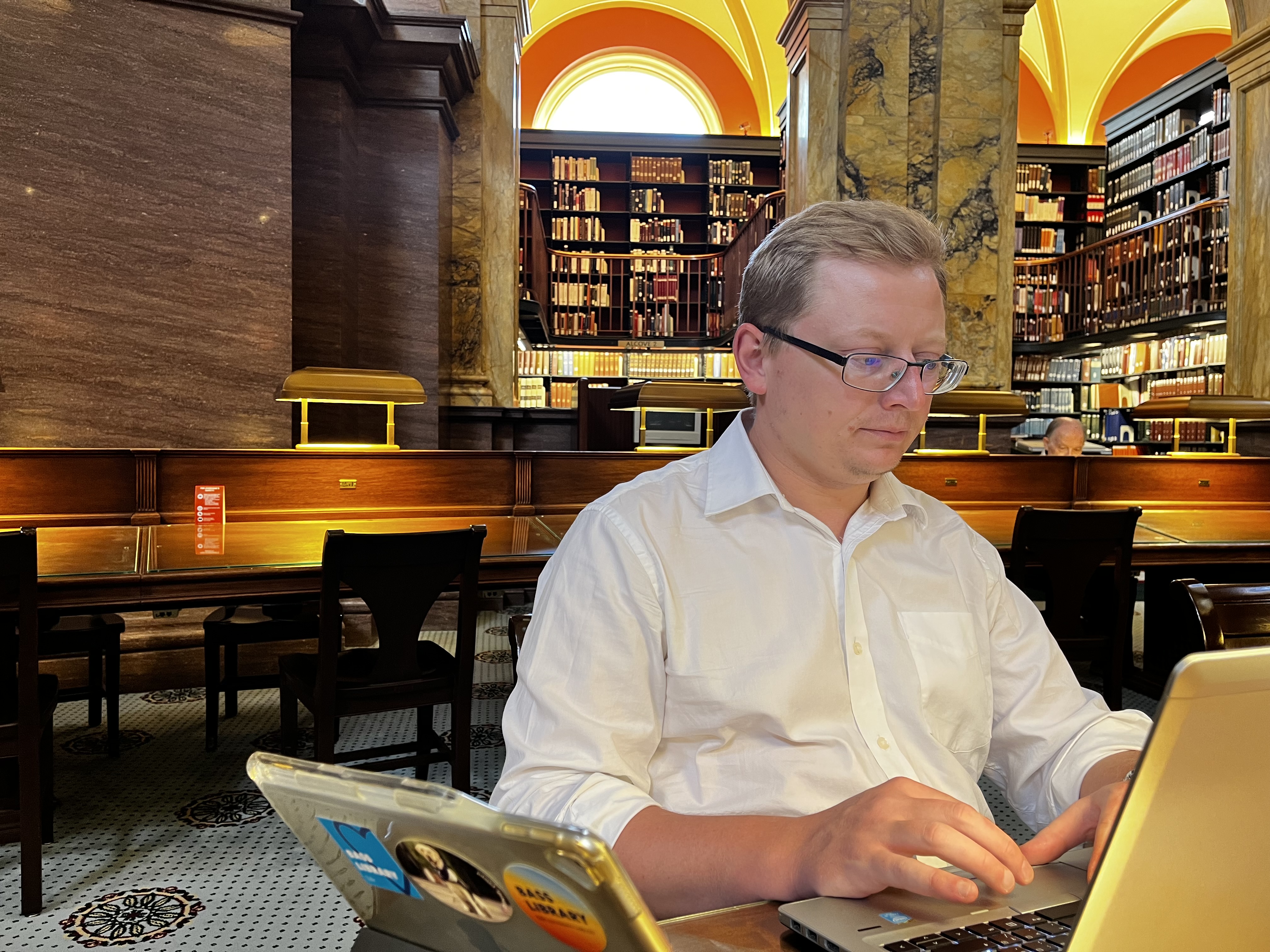 Konrad Szocik working on a laptop while sitting in an old library.